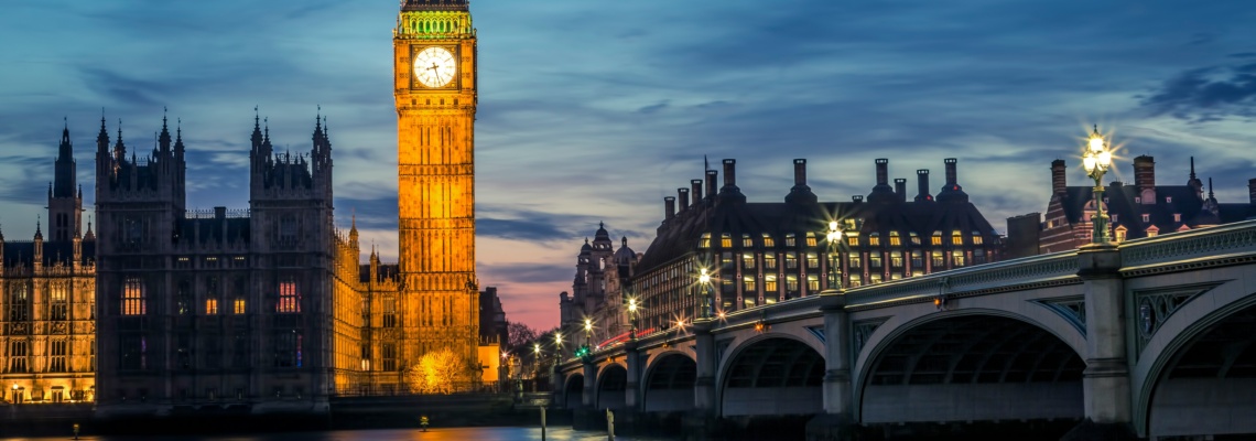 Big Ben and Houses of Parliament illuminated at twilight, reflected in the Thames River with Westminster Bridge